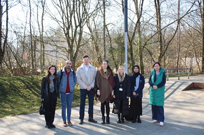 Group of 7 people standing outside with trees in background