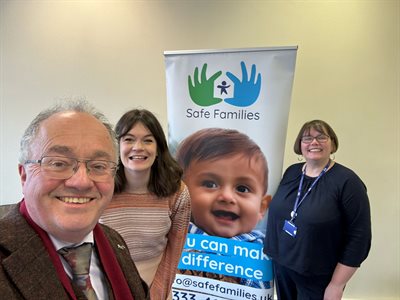 Commissioner with two people in front of a Safe Families banner