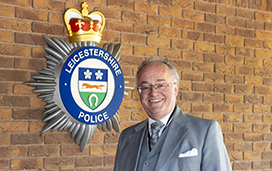 Commissioner standing beside Force Crest on wall