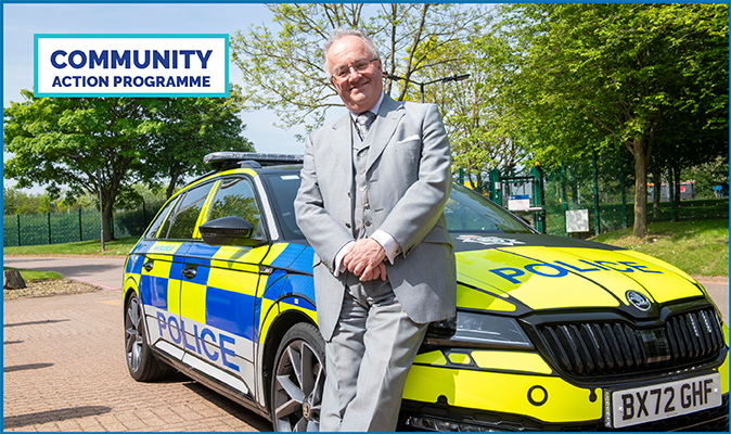 Commissioner leaning against bonnet of police car